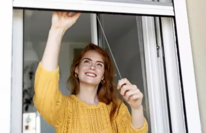 Junge Frau öffnet ein Fenster – richtiges Lüften für effizientes Heizen und geringere Energiekosten mit Tipps der EV Greiz