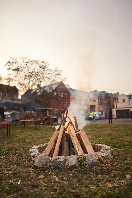 Das Lagerfeuer fängt langsam an zu brennen während die Sonne am Horizont untergeht.