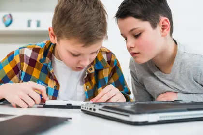 Zwei Jungen fixieren sich konzentriert auf einen Laptop.